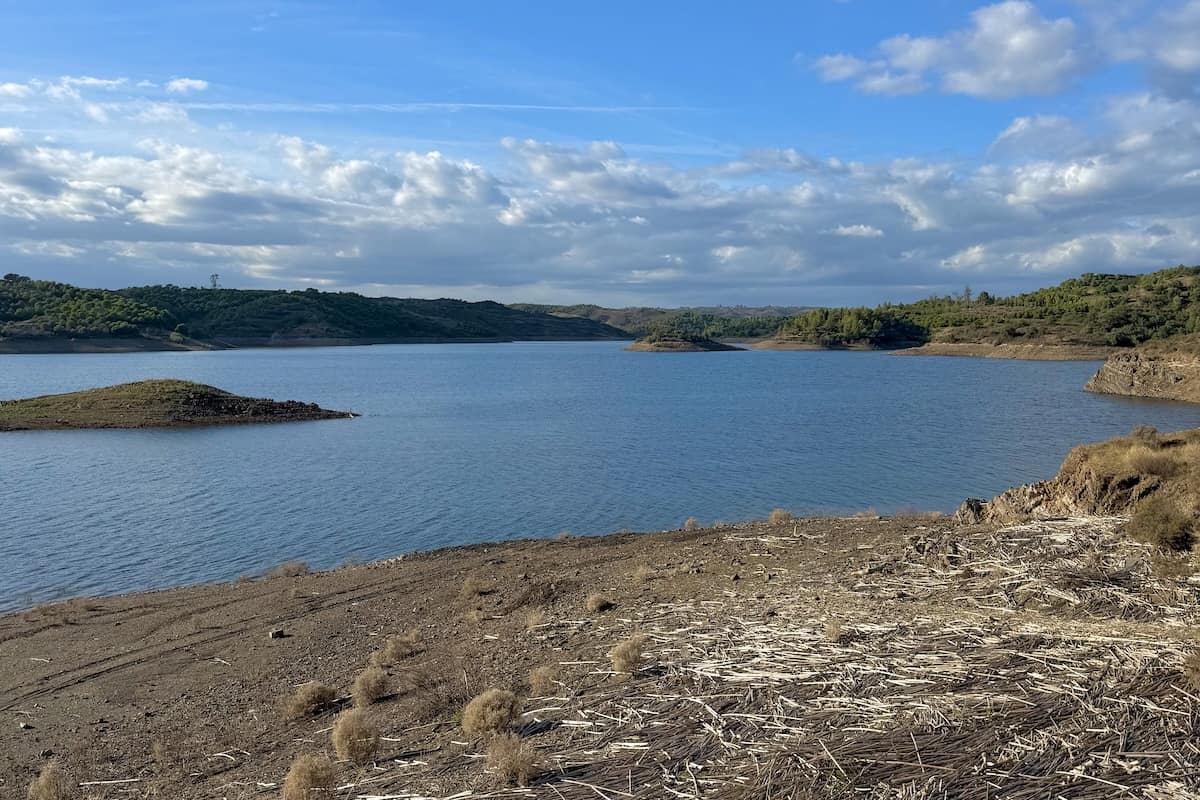 Vista da Barragem de Beliche no sotavento algarvio, com a albufeira e as encostas verdes ao fundo.