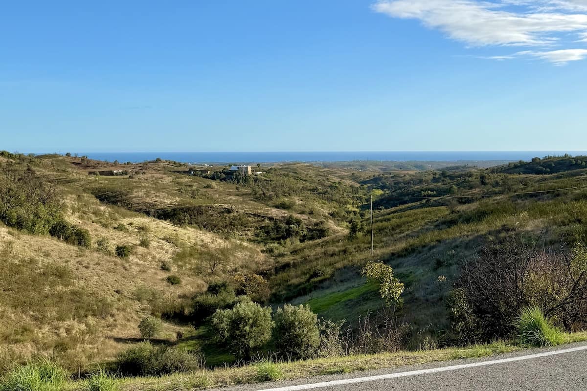 Paisagem de Faz Fato, Tavira, com vista sobre as colinas do barrocal algarvio e o mar ao fundo.