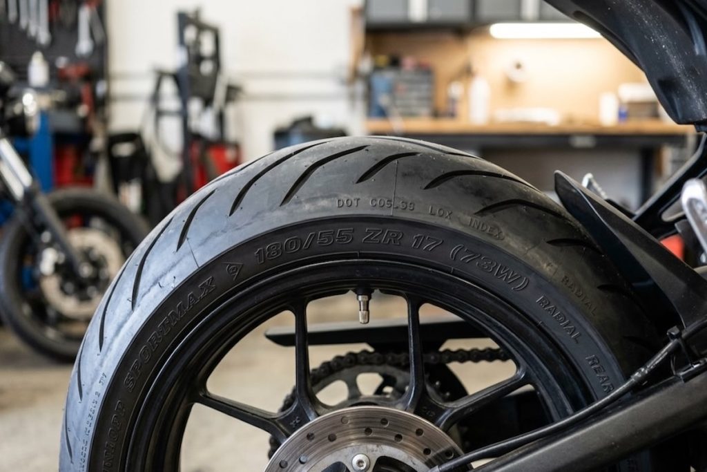 pneu de mota com inscrições laterais visíveis e marcações de medida e índice